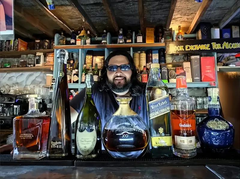Un bartender detrás de una fila de botellas premium en la barra.
